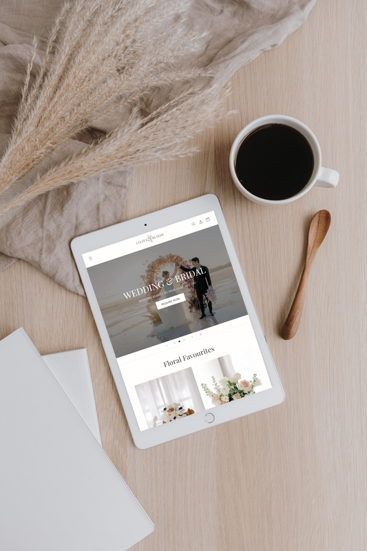 A white iPad sits flat on a desk with "Lilies Bloom" website browser tab open.